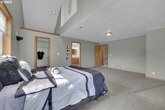 carpeted bedroom featuring a closet, baseboards, a walk in closet, and ensuite bath