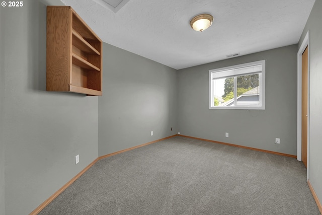 carpeted spare room featuring visible vents and baseboards