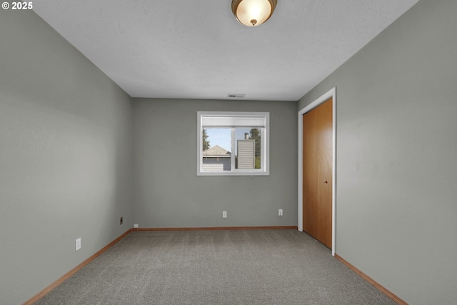 carpeted spare room with baseboards and visible vents