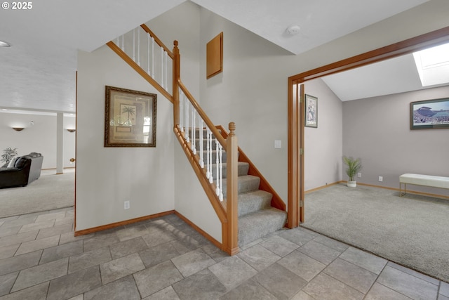 stairway featuring baseboards, carpet flooring, vaulted ceiling, and stone finish floor