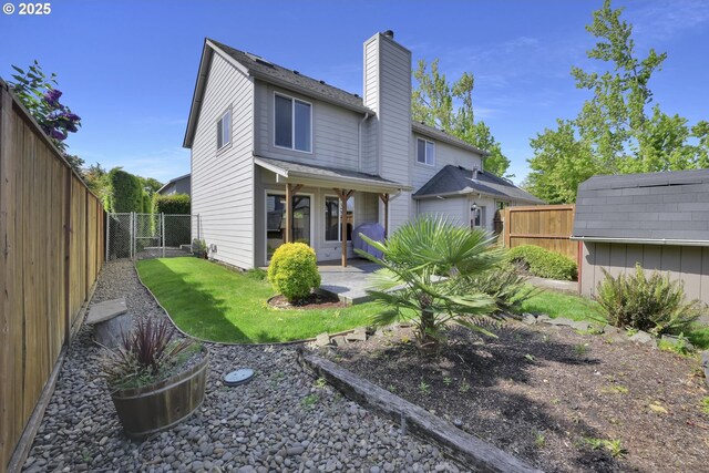rear view of house featuring a chimney, a lawn, an outdoor structure, a fenced backyard, and a patio