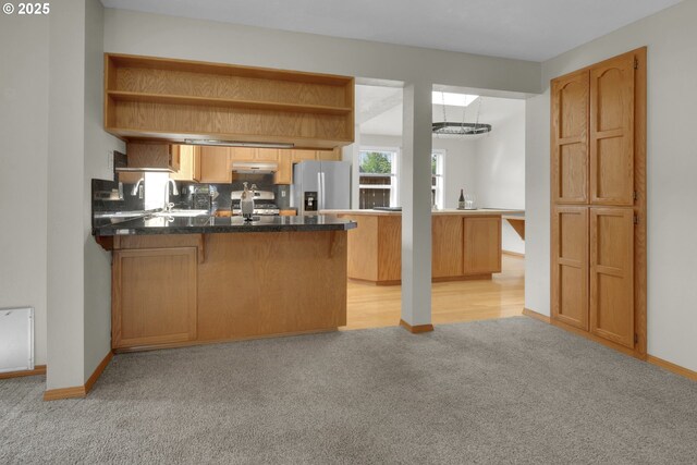 kitchen featuring dark countertops, open shelves, a peninsula, light carpet, and stainless steel appliances