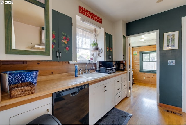 3265 SW 187th Ave, Beaverton, OR 97003 - kitchen featuring black dishwasher, light wood finished floors, white cabinetry, and wood walls