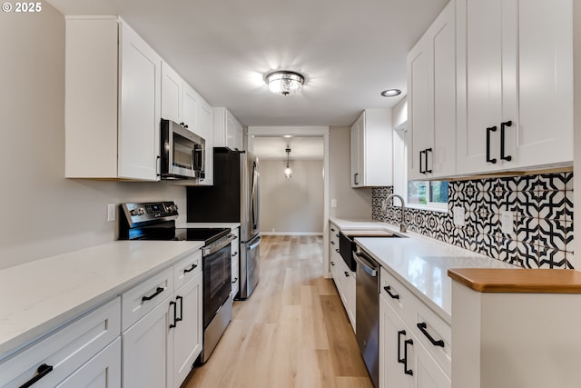5120 Talisman St, Eugene, OR 97405 - kitchen featuring appliances with stainless steel finishes, light wood finished floors, decorative backsplash, white cabinetry, and a sink