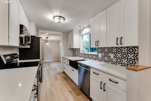 5120 Talisman St, Eugene, OR 97405 - kitchen with stainless steel appliances, a sink, light wood finished floors, tasteful backsplash, and white cabinetry