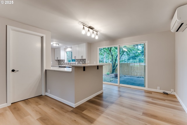 5120 Talisman St, Eugene, OR 97405 - kitchen with a wall mounted AC, light wood-style floors, a peninsula, white cabinetry, and light countertops