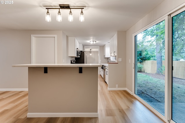 5120 Talisman St, Eugene, OR 97405 - kitchen with light wood-type flooring, a kitchen breakfast bar, freestanding refrigerator, and light countertops