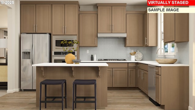 12198 SW Champlin Ln, Beaverton, OR 97007 - kitchen featuring stainless steel appliances, light wood-type flooring, a kitchen breakfast bar, a kitchen island, and light countertops