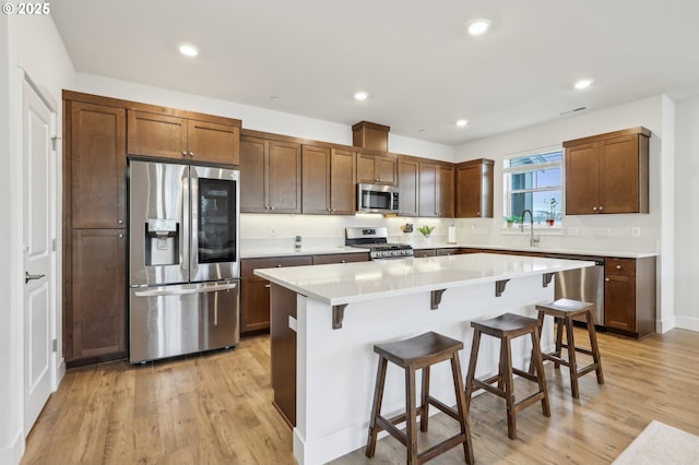 kitchen featuring a breakfast bar, a center island, sink, light hardwood / wood-style floors, and stainless steel appliances