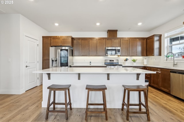 kitchen with a kitchen bar, appliances with stainless steel finishes, a center island, and sink