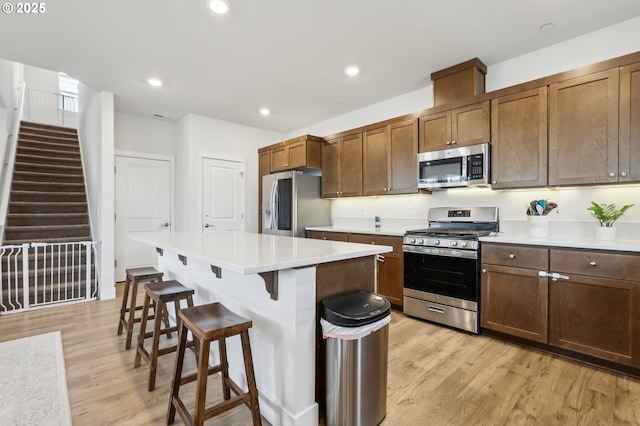 kitchen with a center island, stainless steel appliances, light hardwood / wood-style floors, and a breakfast bar area