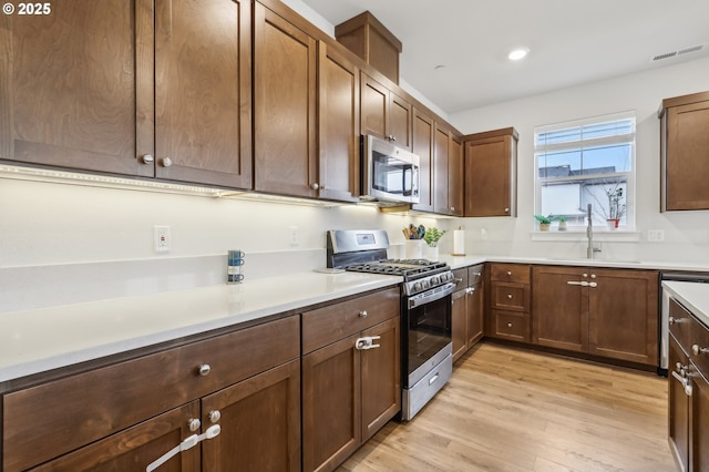 kitchen featuring stainless steel appliances, light hardwood / wood-style flooring, and sink