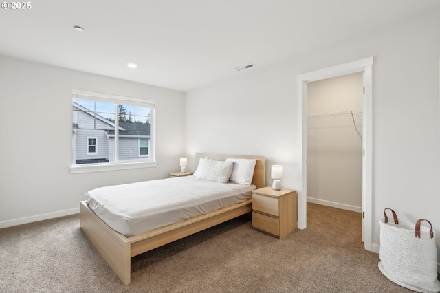 carpeted bedroom featuring a walk in closet and a closet