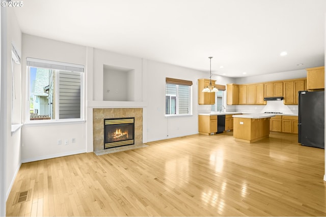 5274 NW Crady Ln, Portland, OR 97229 - kitchen featuring black appliances, light countertops, a kitchen island, a fireplace, and light wood-style floors