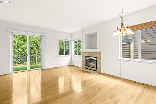 5274 NW Crady Ln, Portland, OR 97229 - unfurnished living room with a chandelier, wood finished floors, and a tiled fireplace