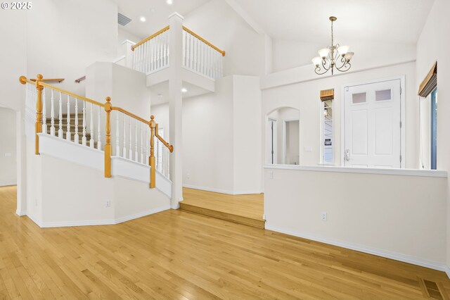 5274 NW Crady Ln, Portland, OR 97229 - foyer entrance featuring wood finished floors, a chandelier, stairs, and high vaulted ceiling