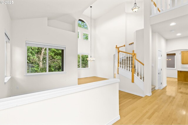 5274 NW Crady Ln, Portland, OR 97229 - hall featuring high vaulted ceiling, light wood finished floors, arched walkways, stairs, and recessed lighting