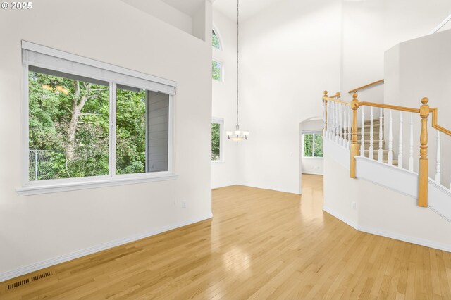 5274 NW Crady Ln, Portland, OR 97229 - empty room featuring a chandelier, wood finished floors, stairway, and a high ceiling