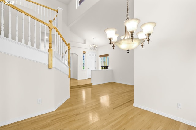 5274 NW Crady Ln, Portland, OR 97229 - unfurnished living room featuring a chandelier, light wood finished floors, a towering ceiling, and stairs