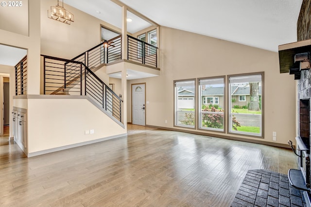 3017 SE Brookwood Ave, Hillsboro, OR 97123 - unfurnished living room featuring stairs, high vaulted ceiling, a chandelier, light wood-style flooring, and baseboards