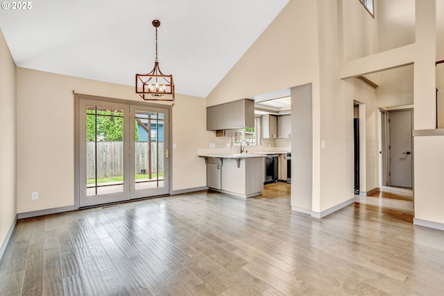 3017 SE Brookwood Ave, Hillsboro, OR 97123 - unfurnished living room with healthy amount of natural light, a chandelier, high vaulted ceiling, and light wood-style flooring