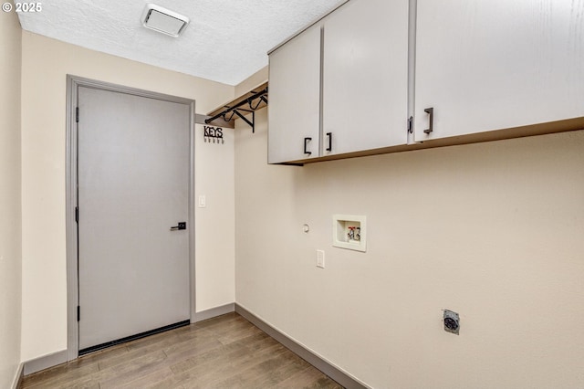 3017 SE Brookwood Ave, Hillsboro, OR 97123 - laundry area featuring cabinet space, hookup for an electric dryer, light wood-style flooring, hookup for a washing machine, and baseboards