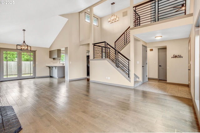 3017 SE Brookwood Ave, Hillsboro, OR 97123 - unfurnished living room with a chandelier, high vaulted ceiling, stairway, plenty of natural light, and wood finished floors
