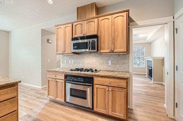 799 NE 70th Ave, Hillsboro, OR 97124 - kitchen with appliances with stainless steel finishes, decorative backsplash, baseboards, light wood finished floors, and a textured ceiling