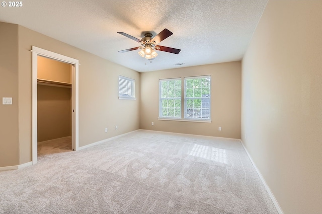 799 NE 70th Ave, Hillsboro, OR 97124 - unfurnished bedroom featuring carpet flooring, a walk in closet, a textured ceiling, baseboards, and ceiling fan