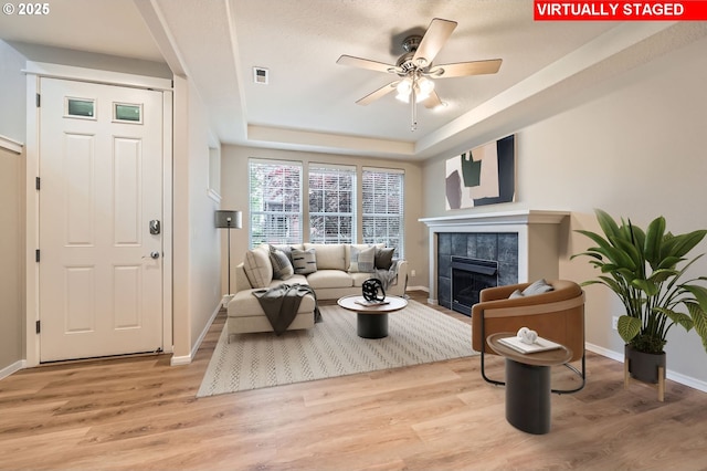 799 NE 70th Ave, Hillsboro, OR 97124 - living room with baseboards, ceiling fan, a raised ceiling, a tile fireplace, and light wood-type flooring