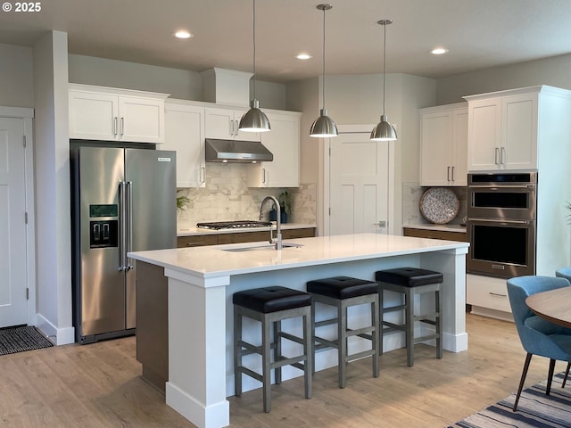 7839 SW Thornbridge Ter Unit 10, Beaverton, OR 97007 - kitchen featuring appliances with stainless steel finishes, under cabinet range hood, light wood-type flooring, backsplash, and recessed lighting