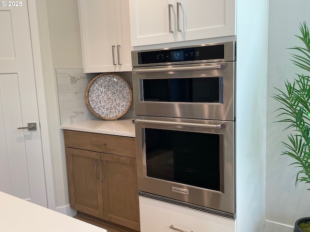 7839 SW Thornbridge Ter Unit 10, Beaverton, OR 97007 - kitchen featuring double oven, backsplash, light countertops, and white cabinetry