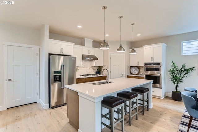 7839 SW Thornbridge Ter Unit 10, Beaverton, OR 97007 - kitchen with stainless steel appliances, under cabinet range hood, a sink, light wood-style floors, and recessed lighting