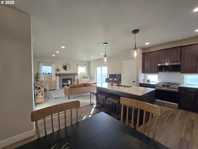 kitchen featuring pendant lighting, sink, appliances with stainless steel finishes, dark brown cabinets, and a center island with sink