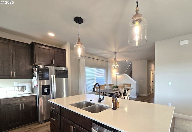 kitchen with dark brown cabinetry, stainless steel appliances, sink, and hanging light fixtures