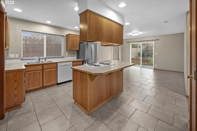 kitchen with sink, light tile patterned floors, white appliances, a breakfast bar, and a kitchen island