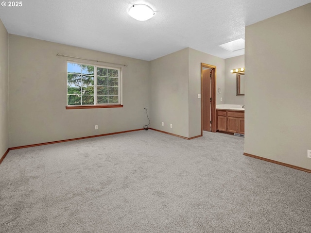 unfurnished room with light carpet, baseboards, a textured ceiling, and a skylight