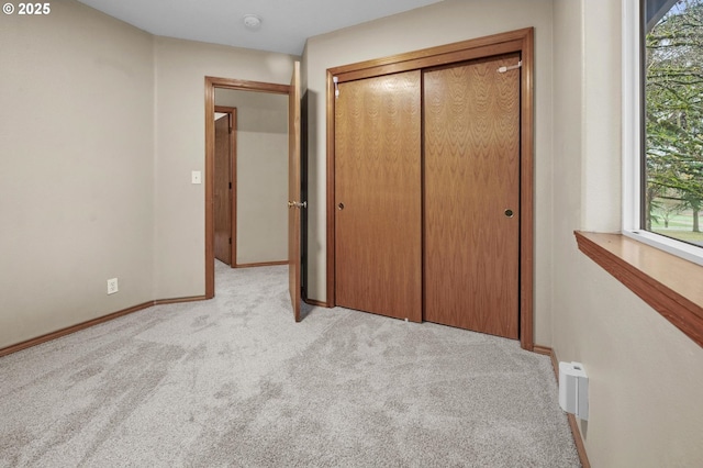 unfurnished bedroom featuring light colored carpet and a closet