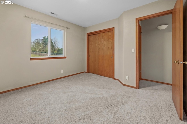 unfurnished bedroom with a closet, visible vents, baseboards, and carpet