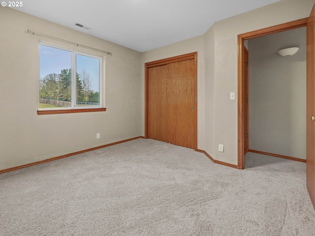 unfurnished bedroom with carpet flooring, visible vents, a closet, and baseboards