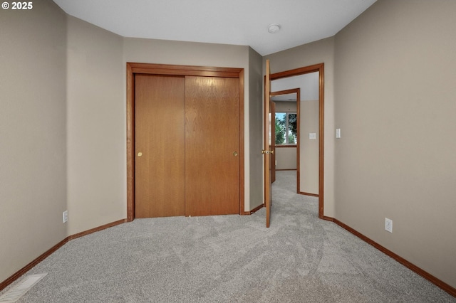 unfurnished bedroom featuring a closet, carpet flooring, visible vents, and baseboards