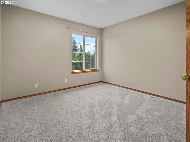 spare room featuring visible vents, baseboards, and carpet