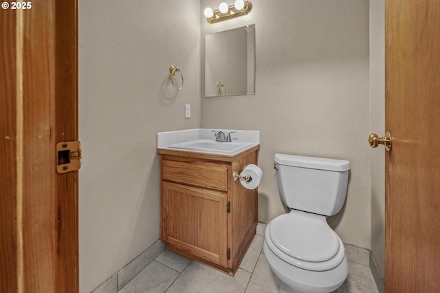 half bath with tile patterned floors, toilet, vanity, and baseboards