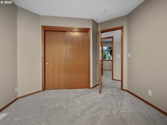 unfurnished bedroom with a closet, baseboards, light colored carpet, and visible vents