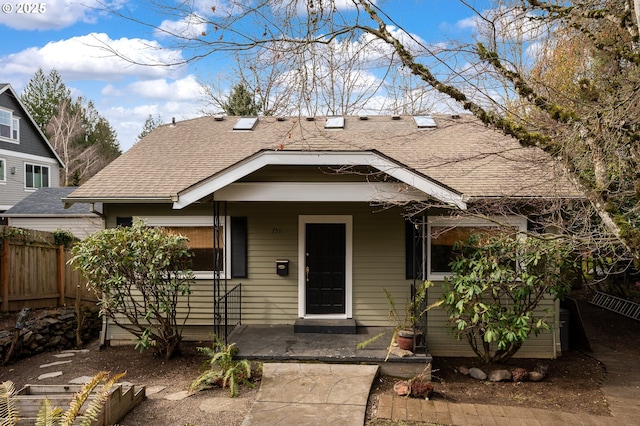 view of front facade with a shingled roof, fence, and a porch