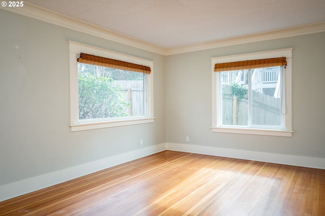 empty room with plenty of natural light, wood finished floors, and crown molding