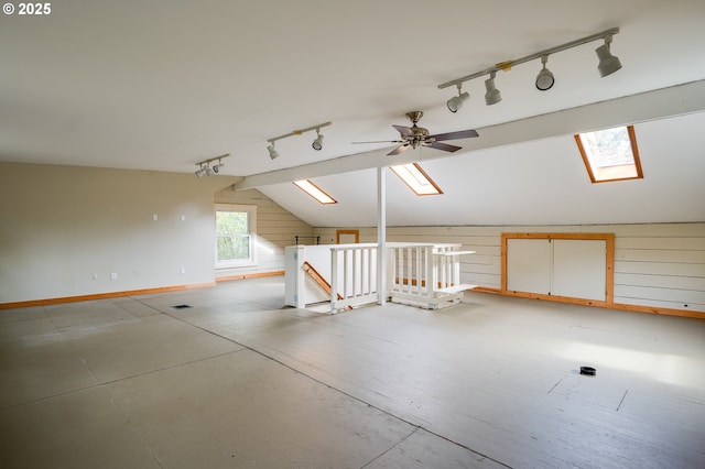 additional living space with wood walls, vaulted ceiling with skylight, and baseboards