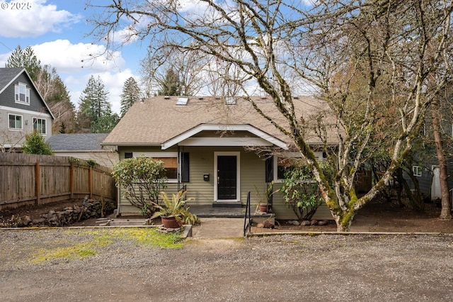 view of front facade featuring roof with shingles and fence