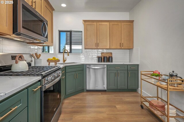 10729 NE Fremont St, Portland, OR 97220 - kitchen with appliances with stainless steel finishes, green cabinetry, a sink, backsplash, and light wood-style flooring