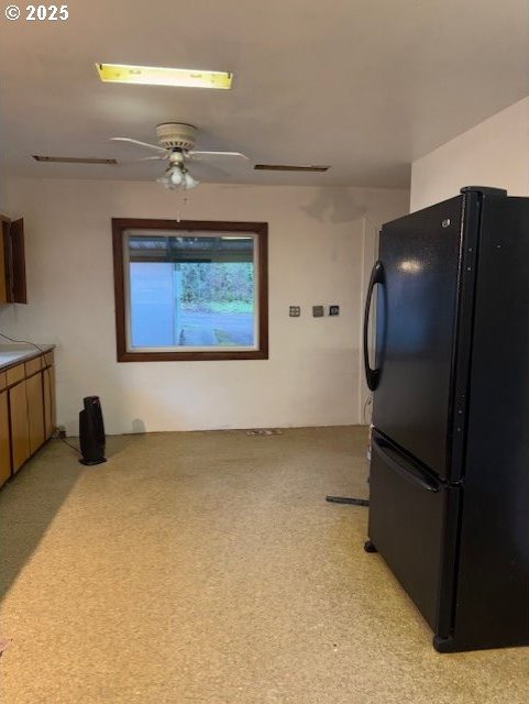 kitchen with light colored carpet, ceiling fan, and black fridge